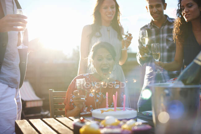 Amigos en la fiesta al aire libre soplando velas en la torta - foto de stock