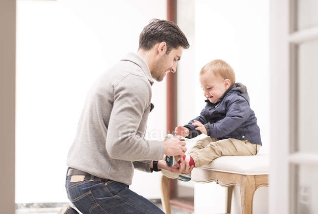Батько допомагає молодому синові одягнути взуття — стокове фото