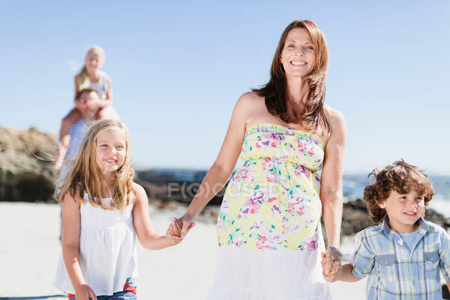 Mutter und Kinder spazieren am Strand — Stockfoto
