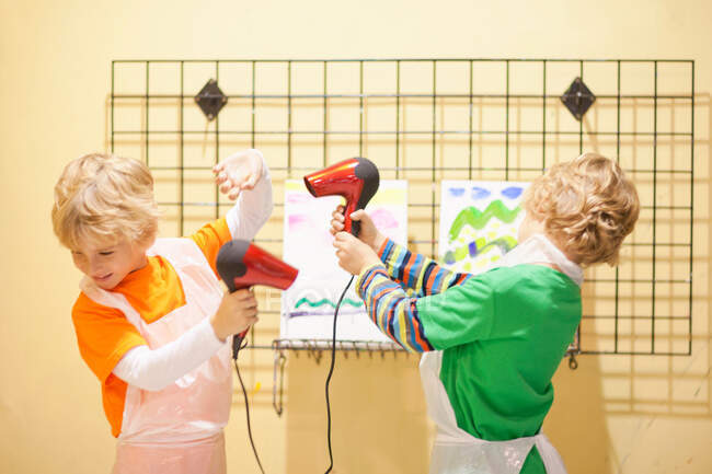 Boys playing with hair dryers whilst drying their paintings — Stock Photo