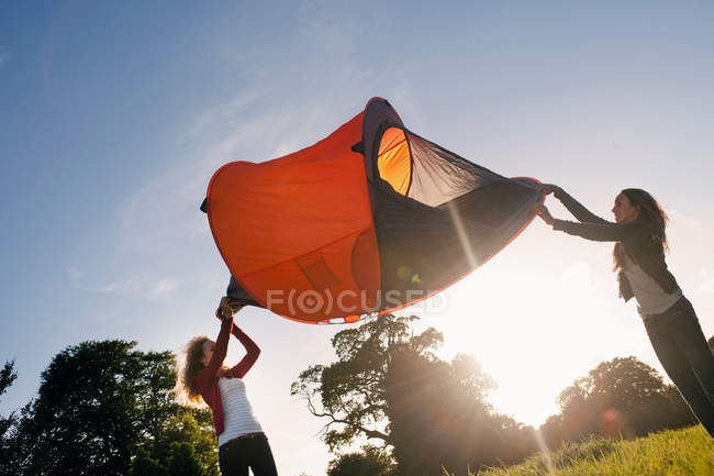 Teenage girls pitching tent in field — Stock Photo