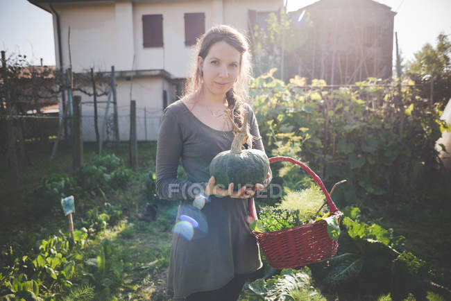 Mujer joven sosteniendo calabaza de cosecha propia - foto de stock