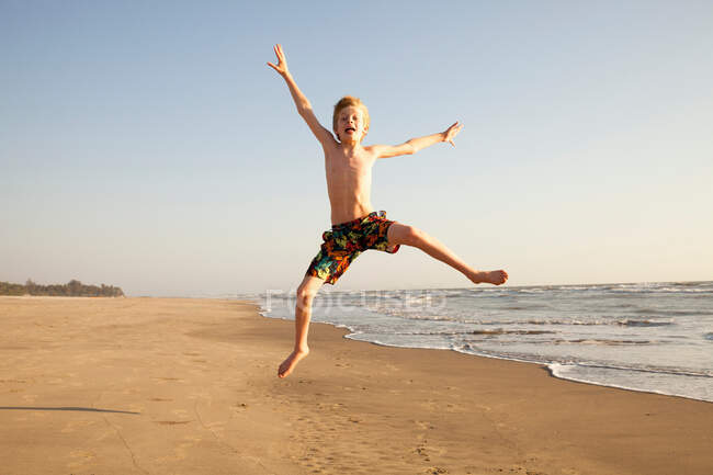 Мальчик прыгает по пляжу, портрет — стоковое фото