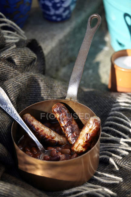 Sacucepan с сосисками и бобами на пороге — стоковое фото