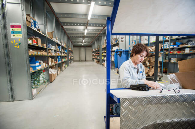 Trabalhadora do armazém preparando ordens no carrinho de entrega — Fotografia de Stock