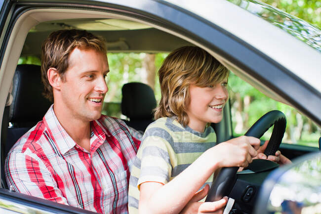 Boy driving car on fathers lap — Stock Photo