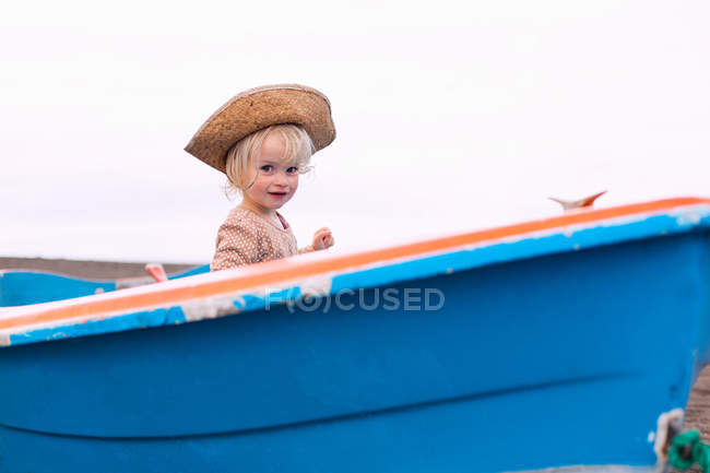 Toddler girl sitting in boat on beach — Stock Photo