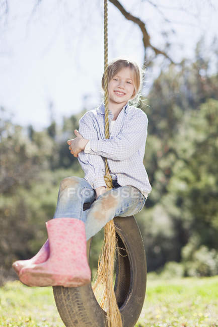Menina sentada no pneu swing ao ar livre — Fotografia de Stock