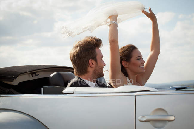 Newlywed couple riding in convertible — Stock Photo