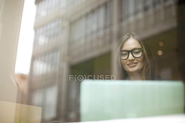 Femme d'affaires à la fenêtre du café à l'aide d'un ordinateur portable, Fribourg, Allemagne — Photo de stock