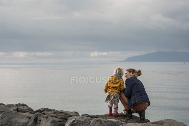 Mother and toddler crouching on harbor wall — Stock Photo