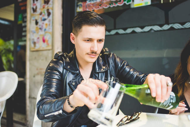 Чоловік поливає пиво в кухоль у тротуарному кафе — стокове фото