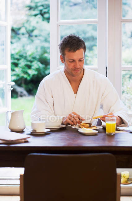 Homem de roupão tomando café da manhã — Fotografia de Stock