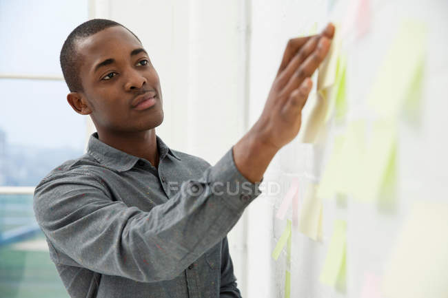 Giovane uomo attaccare note adesive a parete — Foto stock
