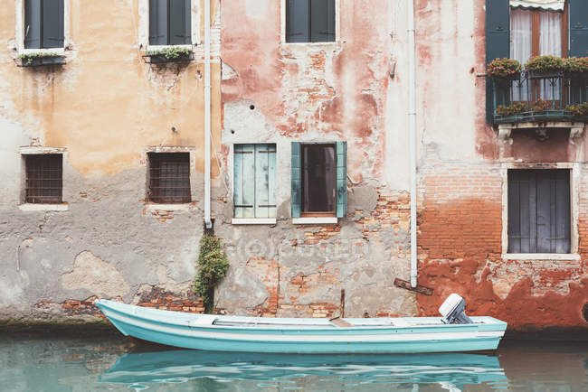 Barco amarrado en el canal al lado de la construcción, Venecia, Italia - foto de stock