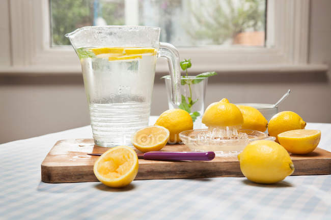 Limones, exprimidor y jarra de agua - foto de stock
