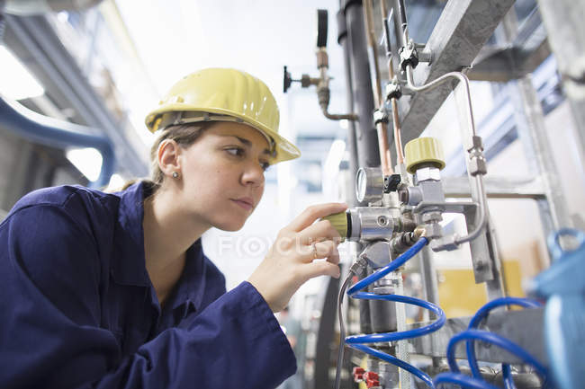 Ingénieur femelle vérifiant les câbles sur les machines industrielles — Photo de stock