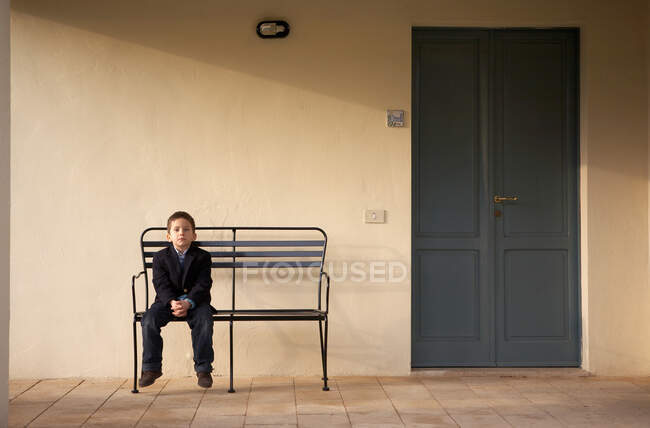 Хлопчик сидить на лавці на відкритому повітрі — стокове фото