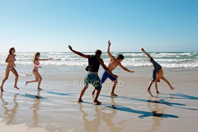 Giovane gruppo frolicking su spiaggia — Foto stock
