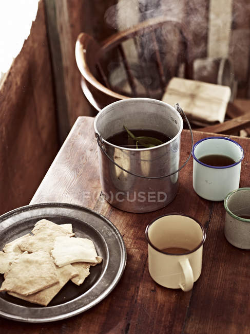 Rustic table with billycan tea and biscuits — Stock Photo