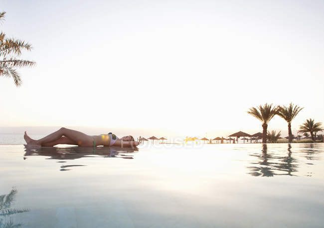Mujer relajante en el borde de la piscina - foto de stock