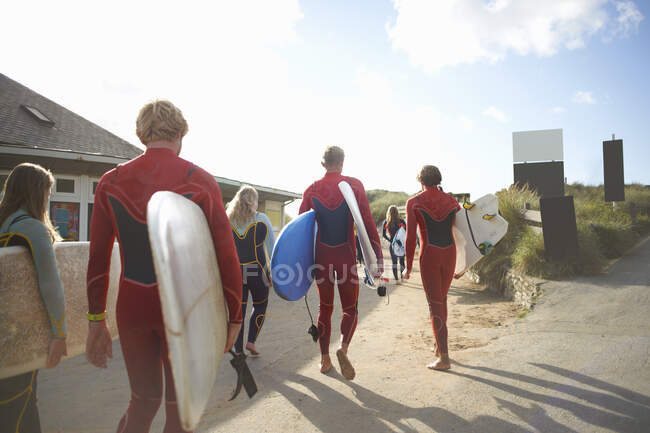 Group of surfers, heading towards beach, carrying surfboards — Stock Photo