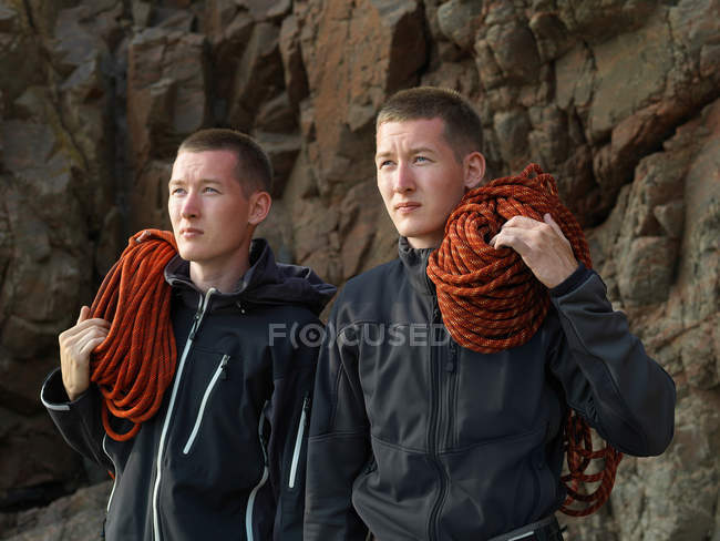 Men carrying loops of rope on beach — Stock Photo