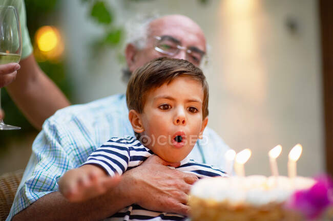 Niño soplando velas en un pastel - foto de stock