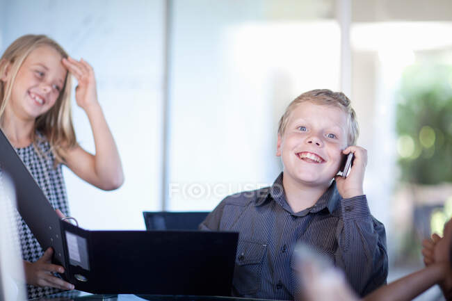 Niños jugando gente de negocios en el escritorio - foto de stock