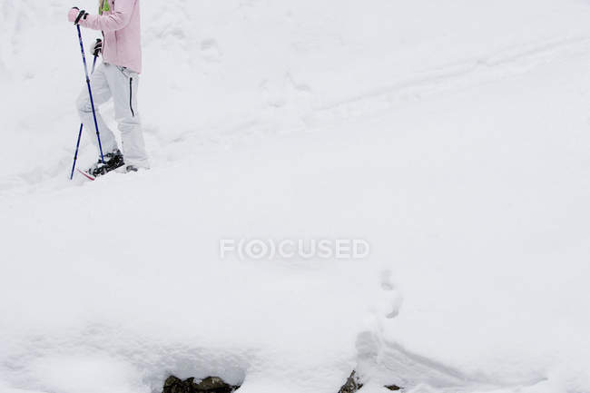 Tiro recortado de fêmea andando em sapatos de neve — Fotografia de Stock