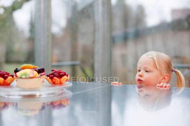 Toddler girl admiring fruit cakes — Stock Photo