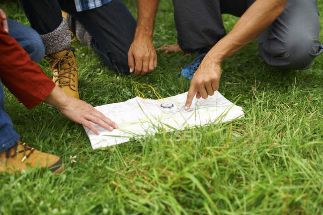 Mains des Amis lisant la carte sur herbe — Photo de stock