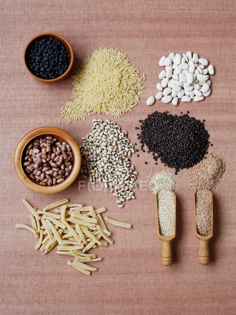Dried pulses and grains in bowls and wooden spoons — Stock Photo