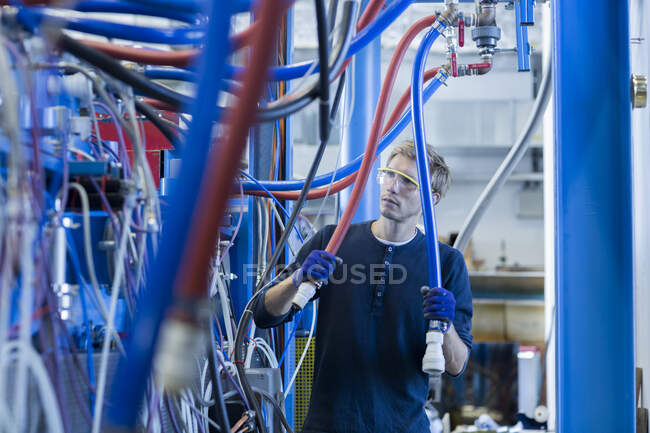 Técnico de fábrica inspecionando cabos de rede — Fotografia de Stock