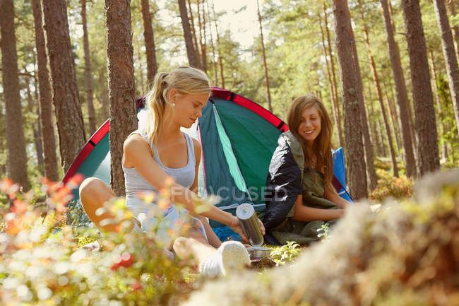 Mujeres instalando camping en el bosque - foto de stock
