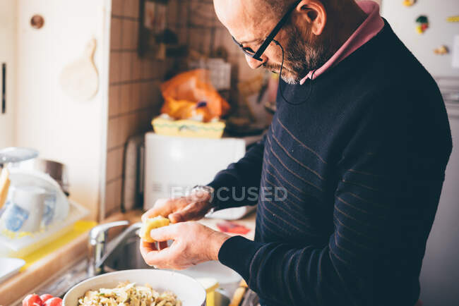Senior man slicing artichokes in kitchen — Stock Photo