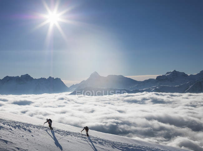 Zwei Bergsteiger an einem schneebedeckten Hang über einem Nebelmeer in einem Alpental, Alpen, Kanton Wallis, Schweiz — Stockfoto
