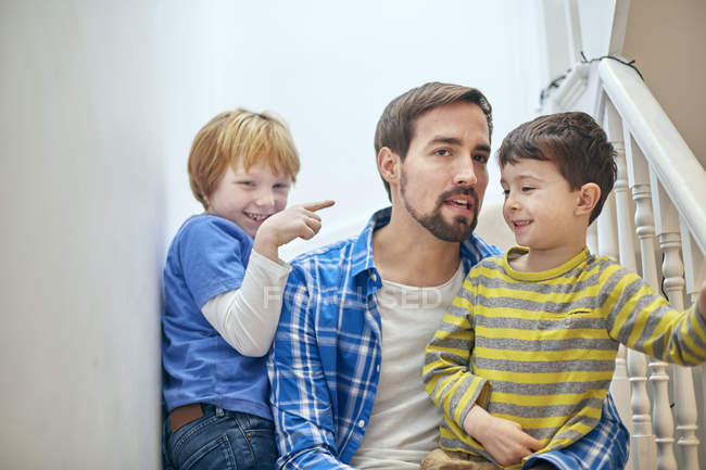 Father and sons sitting on staircase — Stock Photo