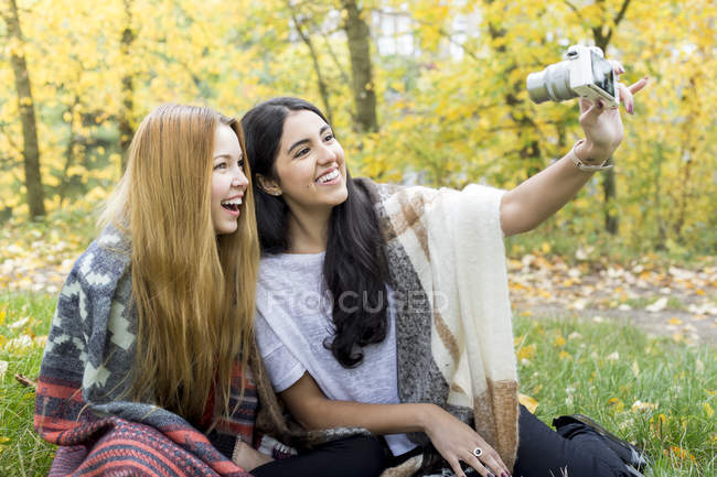 Mujeres jóvenes tomando selfie en el bosque, Hampstead Heath, Londres - foto de stock