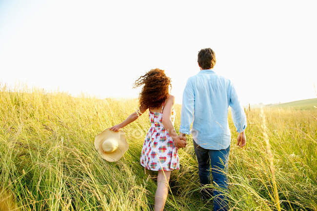 Пара держащихся за руки на пшеничном поле — стоковое фото