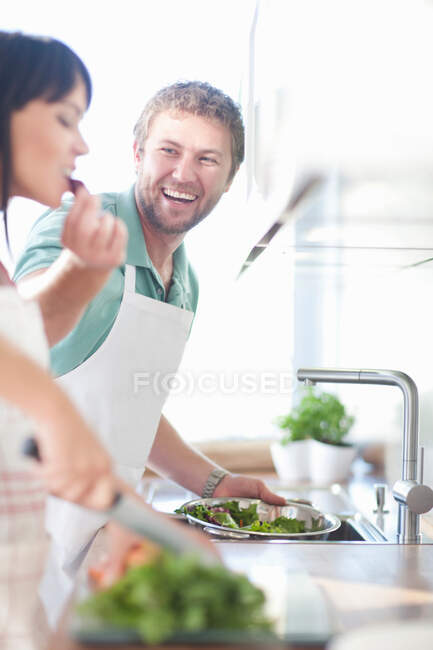 Пара готовит еду, мужчина кормит женщину — стоковое фото