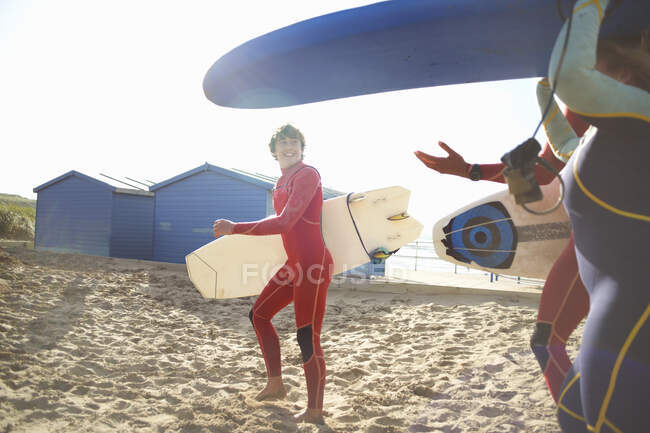 Groupe de surfeurs sur la plage, transportant des planches de surf — Photo de stock
