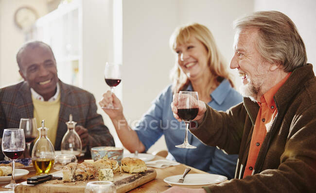 Amigos mayores haciendo un brindis en la cena - foto de stock
