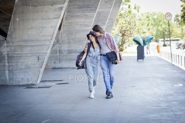 Jeune couple marchant par bâtiment — Photo de stock