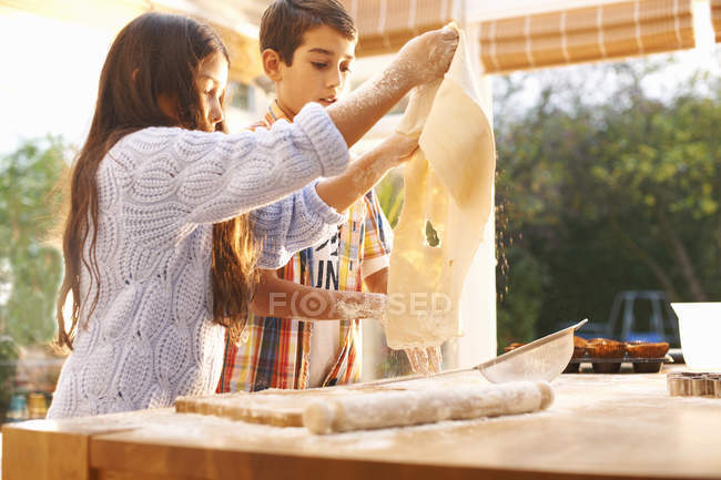 Children making dough in kitchen at home — Stock Photo