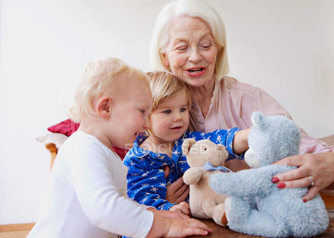 Бабушка играет с двумя малышами — стоковое фото