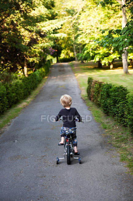 Rückansicht Junge reitet Dreirad auf Weg — Stockfoto