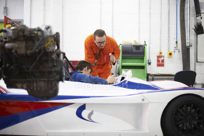 College mechanic students checking racing car in repair garage — Stock Photo