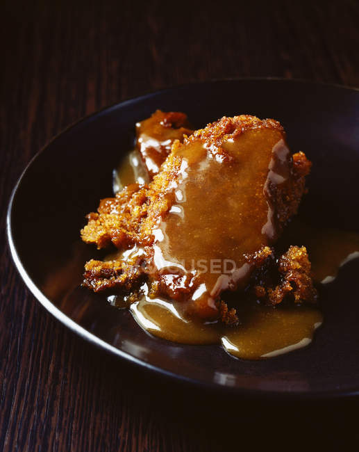 Sticky toffee pudding covered in toffee sauce — Stock Photo