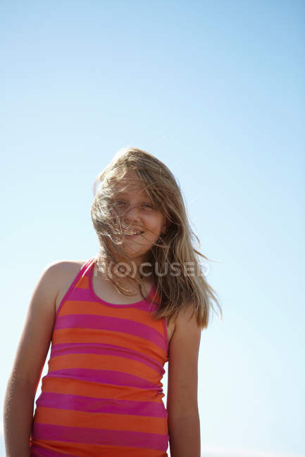 Menina sorridente com o cabelo soprando no vento — Fotografia de Stock